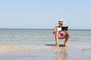 Mann sitzt auf einem Stuhl am Strand und liest mann-am-strand-auf-stuhl